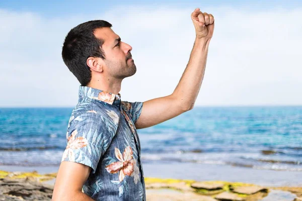 Sahilde küçük işareti yapma çiçek forması ile yakışıklı adam