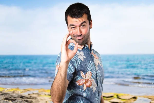 Stilig man med blomma skjorta att göra Ok logga på stranden — Stockfoto