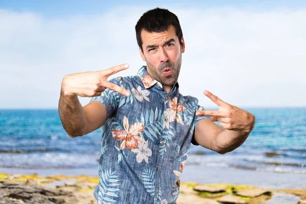 Hombre guapo con camisa de flores haciendo gesto de victoria en la playa —  Fotos de Stock