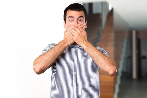 Handsome man covering his mouth inside house