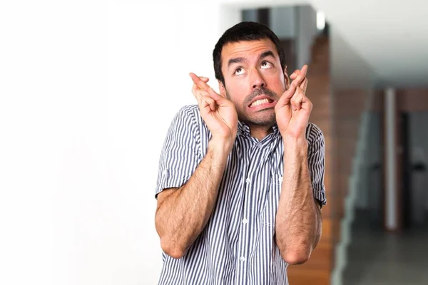 Knappe man met zijn vingers oversteken in huis — Stockfoto