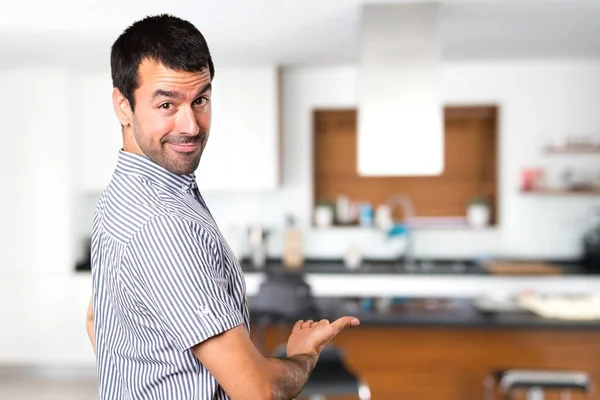 Bonito homem apresentando algo dentro da casa — Fotografia de Stock