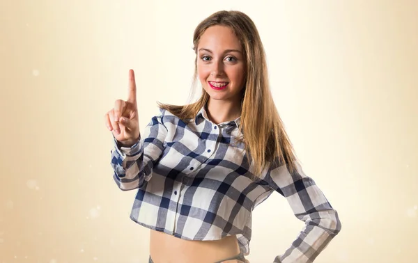 Blonde teen girl counting one on ocher background — Stock Photo, Image