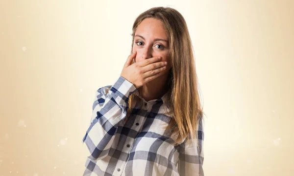 Blond tonåring flicka som täcker hennes mun på ockra bakgrund — Stockfoto