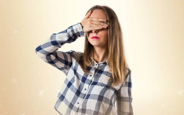 Rubia adolescente chica cubriendo sus ojos en ocre fondo —  Fotos de Stock