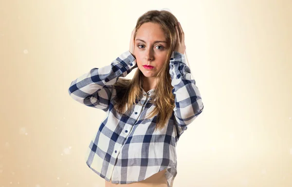 Rubia adolescente chica cubriendo sus oídos en ocre fondo —  Fotos de Stock