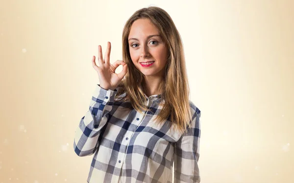 Blond tonåring flicka att göra små tecken på ockra bakgrund — Stockfoto