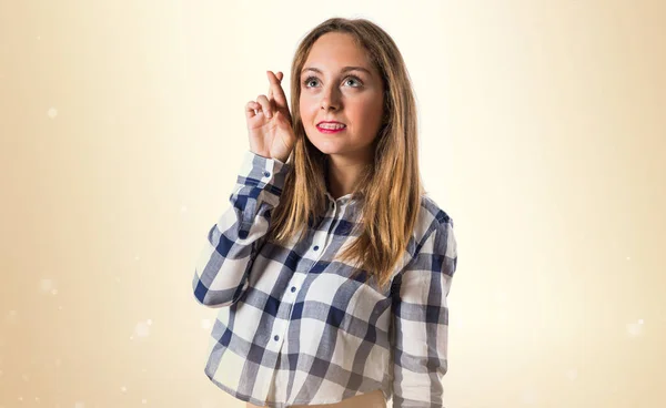 Loira menina adolescente com os dedos cruzando no fundo ocre — Fotografia de Stock