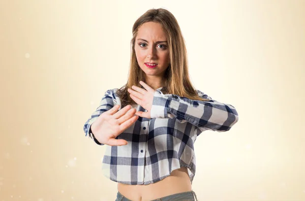 Blondes Teenie-Mädchen macht Stoppschild auf ockerfarbenem Hintergrund — Stockfoto