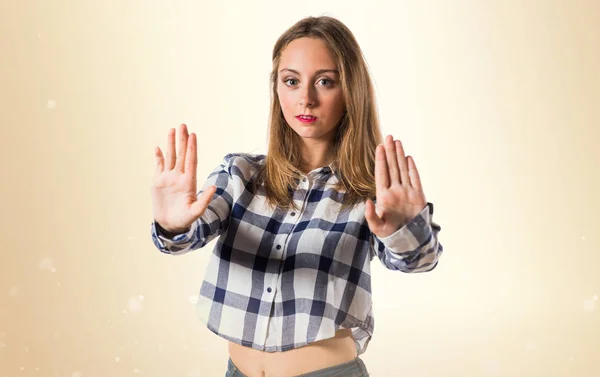 Blond tonåring flicka att göra stoppskylt på ockra bakgrund — Stockfoto