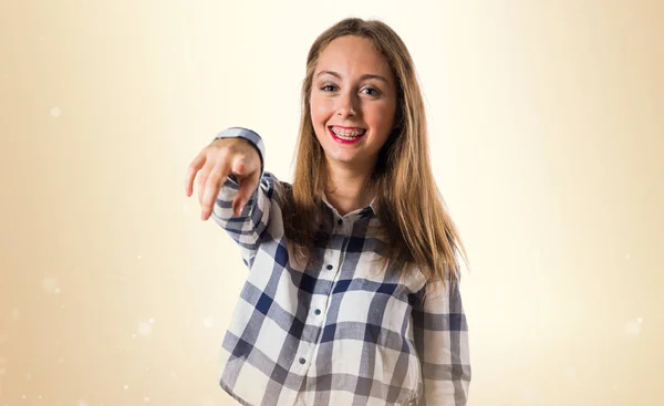 Blondes Teenie-Mädchen zeigt nach vorne auf ockerfarbenem Hintergrund — Stockfoto