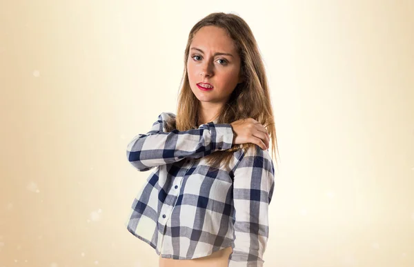 Blonde teen girl with shoulder pain on ocher background — Stock Photo, Image