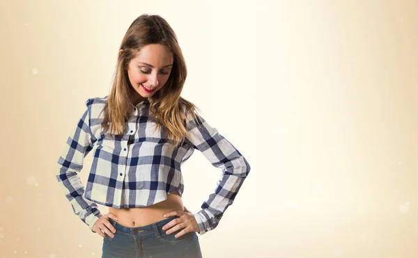 Blondes Teenie-Mädchen schaut auf ockerfarbenen Hintergrund herab — Stockfoto