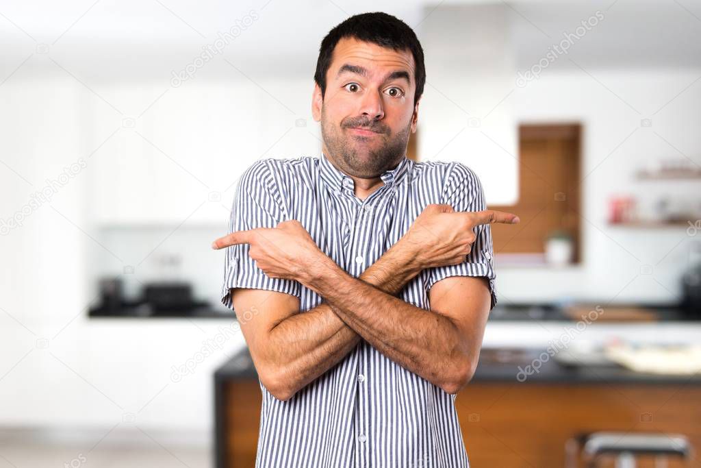 Handsome man pointing to the laterals having doubts inside house