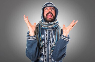 Gri arka plan üzerinde kış giysileri ile sinirli adam