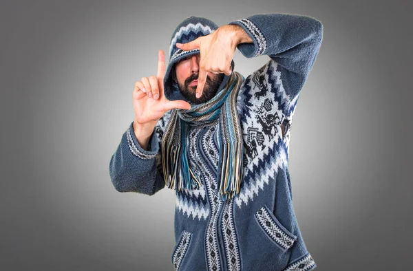 Hombre con ropa de invierno enfocando con los dedos en gris backgr — Foto de Stock