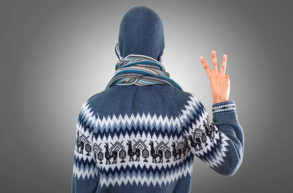 Uomo con abiti invernali contando tre su sfondo grigio — Foto Stock