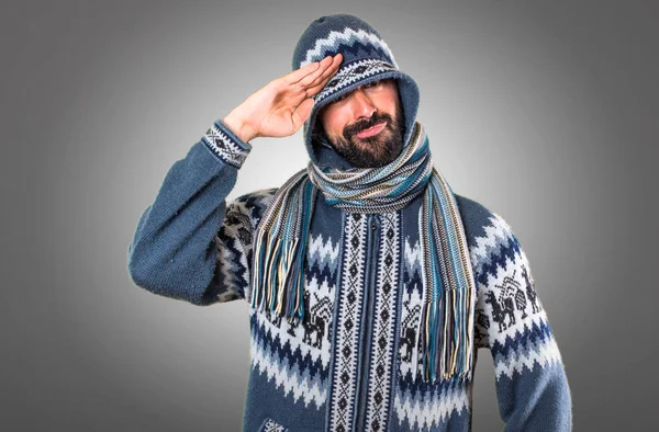 Hombre con ropa de invierno saludando sobre fondo gris — Foto de Stock