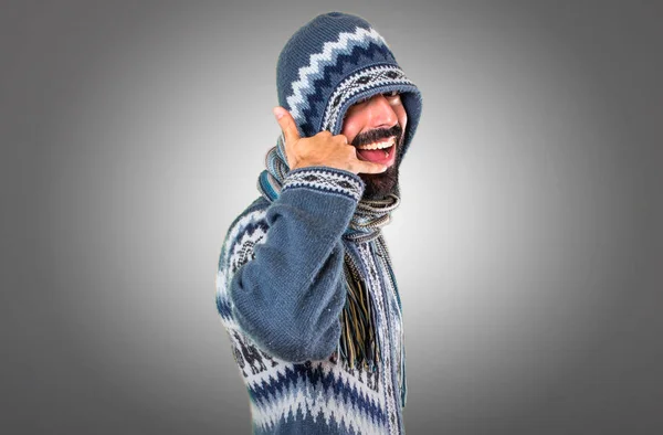 Man with winter clothes making phone gesture on grey background — Stock Photo, Image