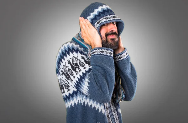 Hombre con ropa de invierno cubriéndose las orejas sobre fondo gris — Foto de Stock