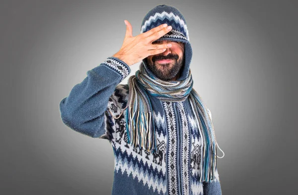 Mann mit Winterkleidung verdeckt die Augen auf grauem Hintergrund — Stockfoto