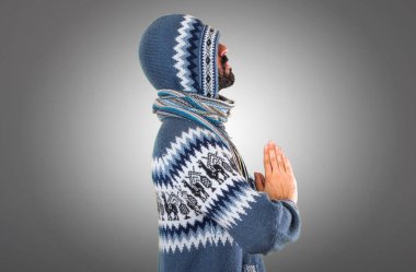 Kış giysileri gri arka plan üzerinde zen pozisyonda olan adam