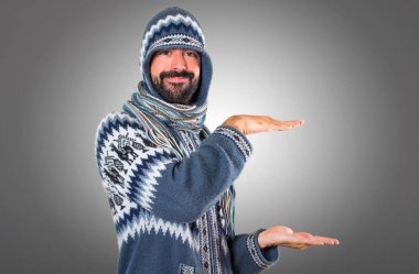 Adam bir şey gri arka plan üzerinde tutan kış giysileri ile