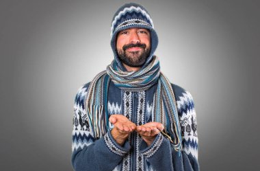 Adam bir şey gri arka plan üzerinde tutan kış giysileri ile