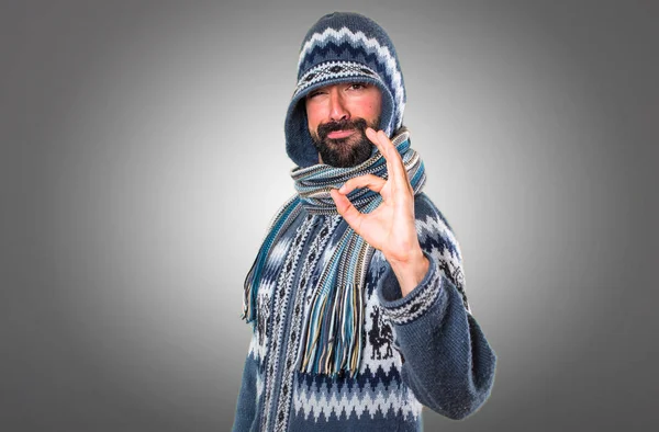 Hombre con ropa de invierno haciendo signo OK sobre fondo gris — Foto de Stock