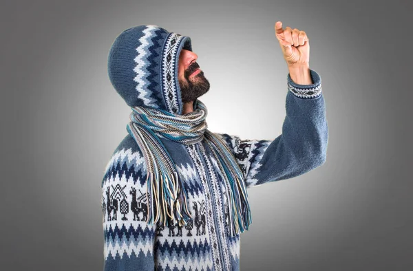 Adam küçük yapma kış giysileri ile gri arka plan üzerinde oturum