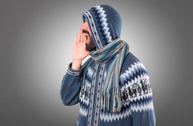 Adam gri arka plan üzerine bağırarak kış giysileri ile