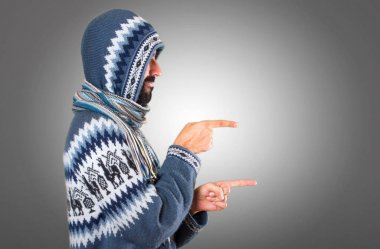 Kış giysileri üzerinde gri backgrou lateral işaret eden adamla