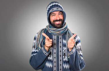 Kış giysileri gri arka plan üzerine açık işaret eden adamla