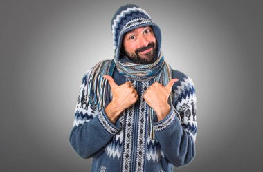 Adam gri arka plan üzerinde başparmak ile kış giysileri ile