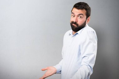 Dokulu arka plan üzerinde önemsiz jest yapma sakallı yakışıklı adam