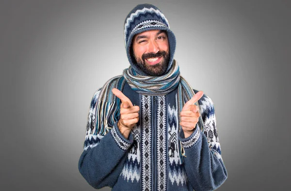 Kış giysileri gri arka plan üzerine açık işaret eden adamla