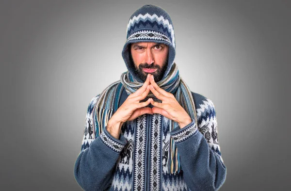 Mann mit Winterkleidung denkt auf grauem Hintergrund — Stockfoto