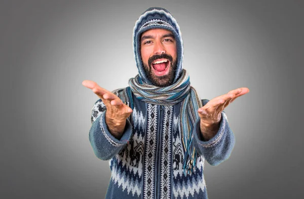 Mannen med vinterkläder presentera något på grå bakgrund — Stockfoto