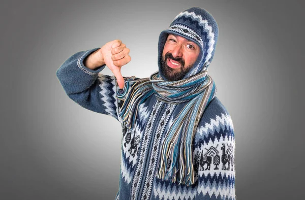 Mann mit Winterkleidung macht schlechtes Signal auf grauem Hintergrund — Stockfoto