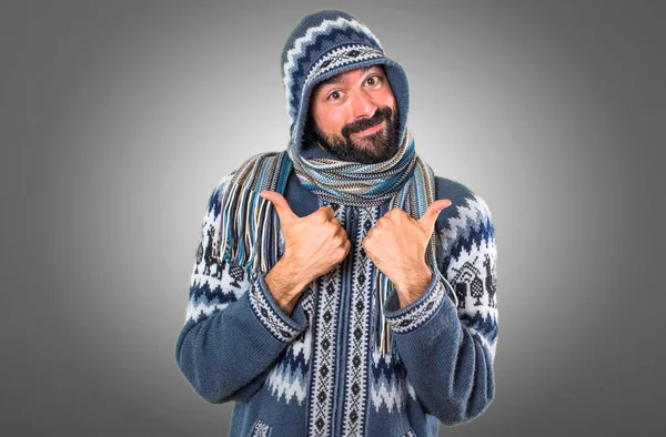 Człowiek z zimowych ubrań z kciuk na szarym tle — Zdjęcie stockowe
