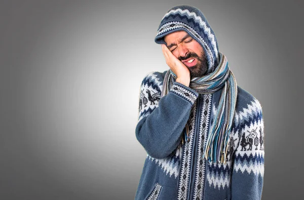 Mannen med vinter kläder gör sömn gest på grå bakgrund — Stockfoto