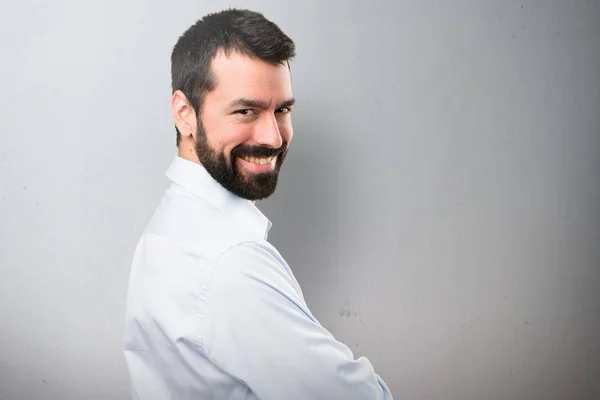 Bonito homem com barba com os braços cruzados em fundo texturizado — Fotografia de Stock