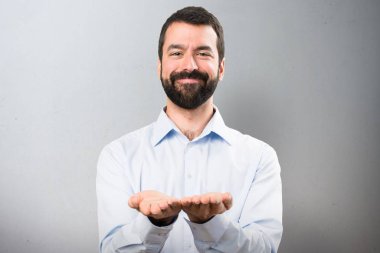 Bir şey dokulu arka plan üzerinde tutan sakallı yakışıklı adam