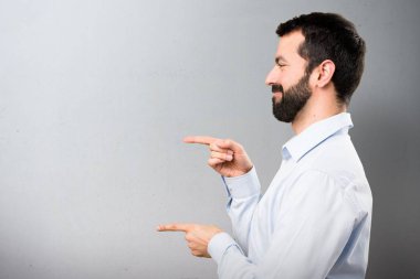 Lateral dokulu arka plan üzerinde işaret eden sakallı yakışıklı adam