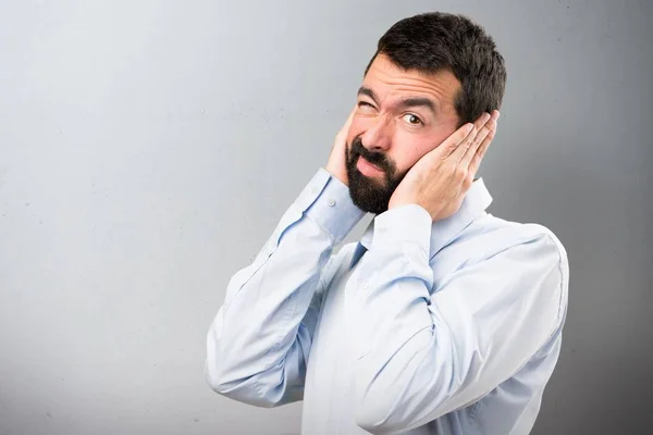 Knappe man met baard die betrekking hebben op zijn oren op gestructureerde achtergrond — Stockfoto