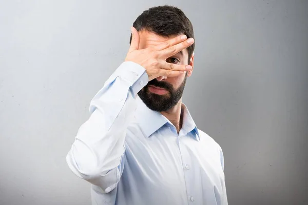 Schöner Mann mit Bart, der seine Augen vor strukturiertem Hintergrund verdeckt — Stockfoto