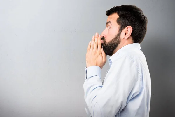 Handsome man with beard pleading on textured background — Stock Photo, Image