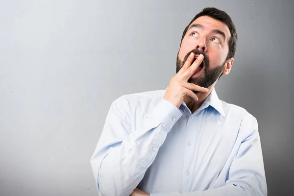 Bonito homem com barba fazendo gesto surpresa no fundo texturizado — Fotografia de Stock