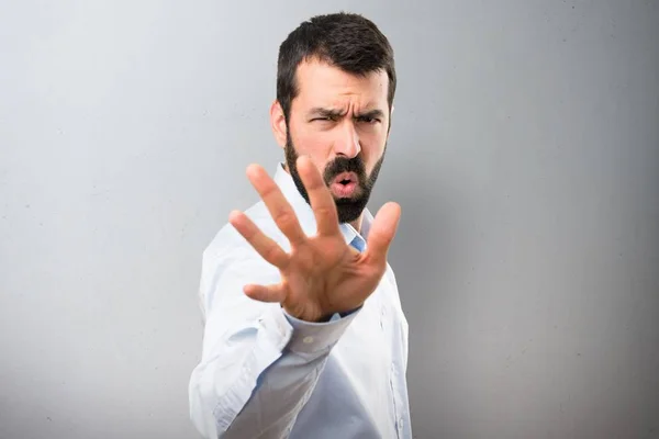 Hombre guapo con barba haciendo señal de stop sobre fondo texturizado —  Fotos de Stock