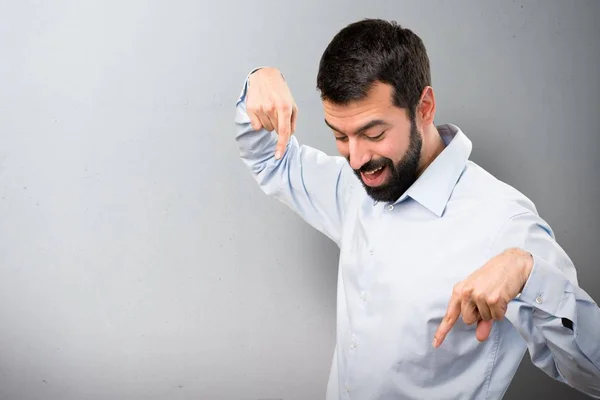 Schöner Mann mit Bart, der auf strukturiertem Hintergrund nach unten zeigt — Stockfoto